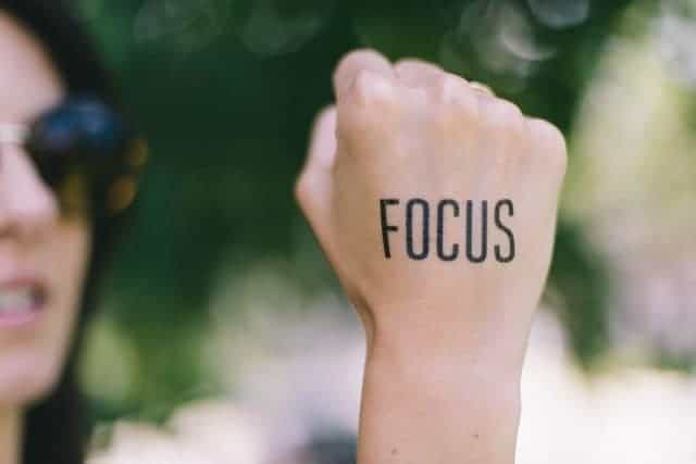 Woman wearing sunglasses with fist held up, FOCUS tattooed on it