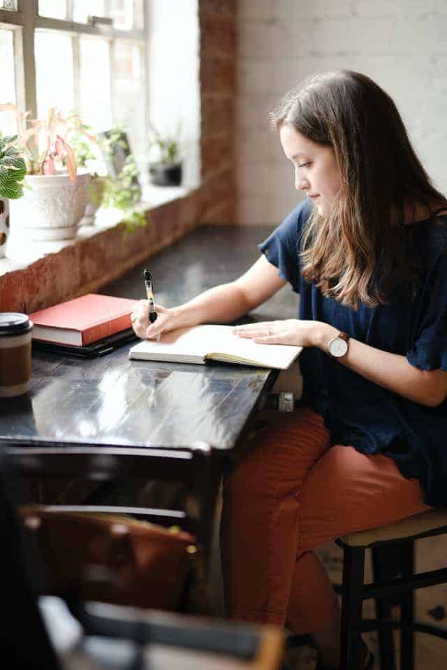 Woman at coffee shop writing in her journal